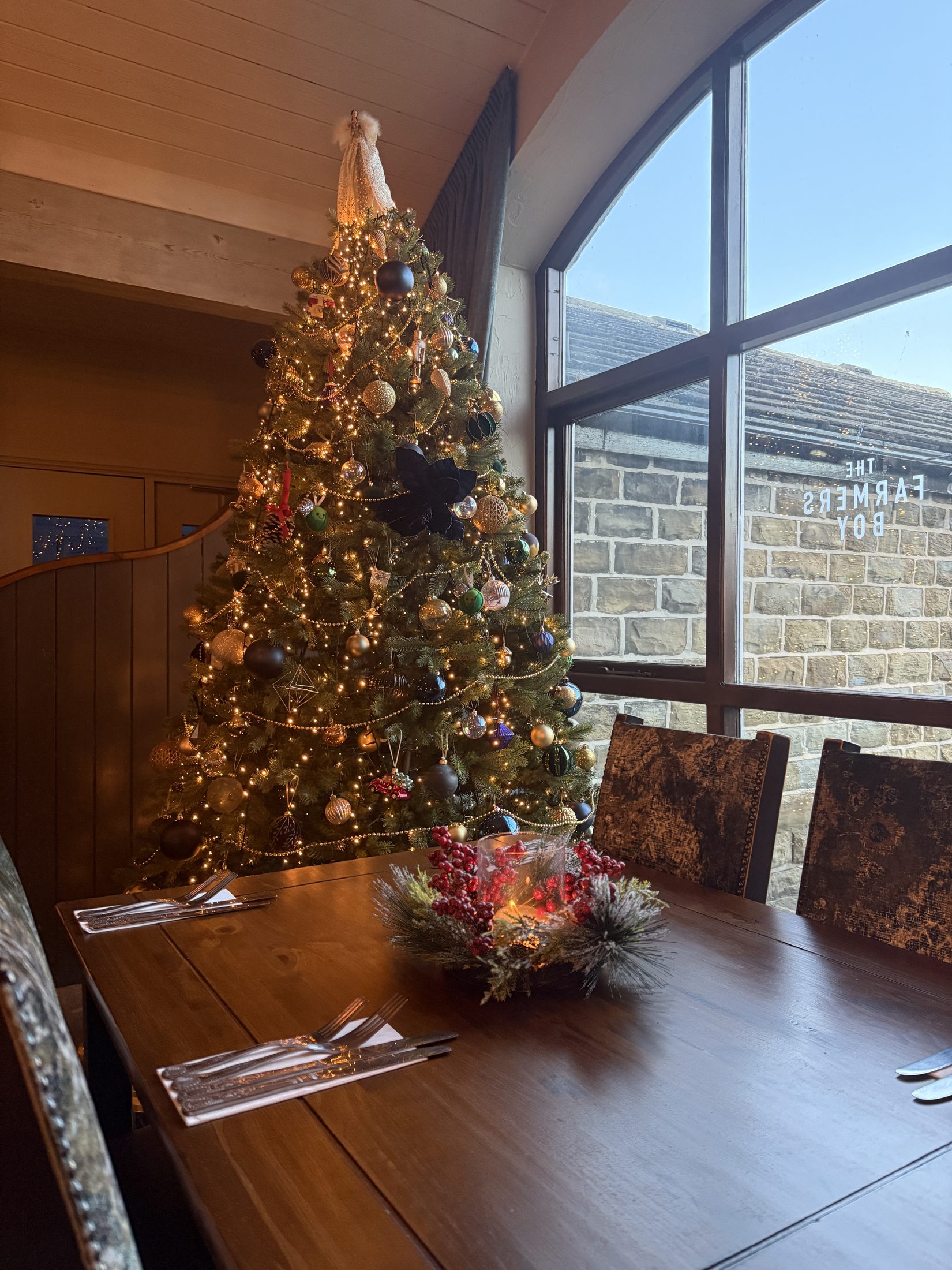 A decorated Christmas tree beside set dining tables at The Farmers Boy in Shepley